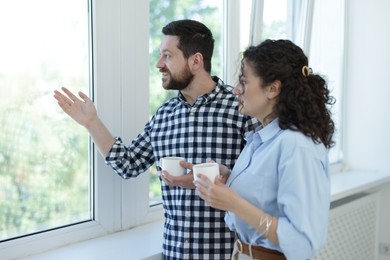 Photo of Colleagues looking out window during coffee break in office