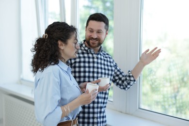 Photo of Colleagues looking out window during coffee break in office