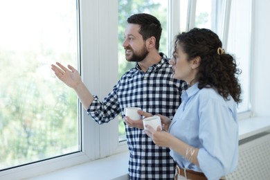 Photo of Colleagues looking out window during coffee break in office