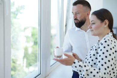 Photo of Colleagues looking out window during coffee break in office