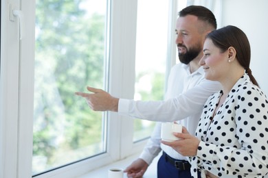 Photo of Colleagues looking out window during coffee break in office