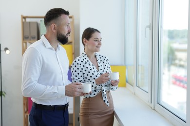 Photo of Colleagues looking out window during coffee break in office