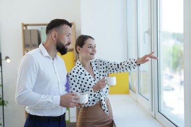 Photo of Colleagues looking out window during coffee break in office