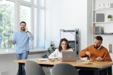 Photo of Colleagues eating and chatting during lunch break in office