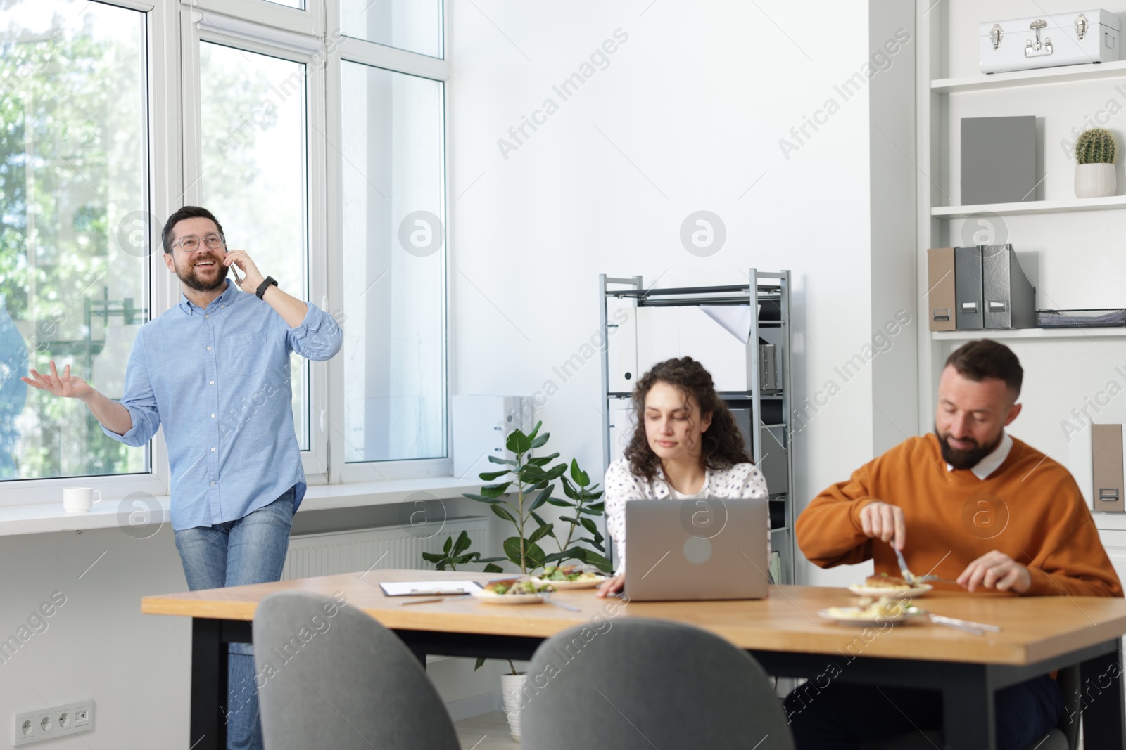 Colleagues eating and chatting during lunch break in office Photo of Colleagues eating and chatting during lunch break in office