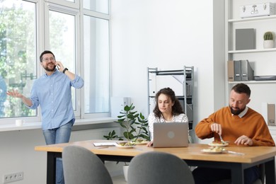 Photo of Colleagues eating and chatting during lunch break in office