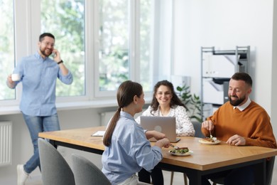 Photo of Colleagues eating and chatting during lunch break in office