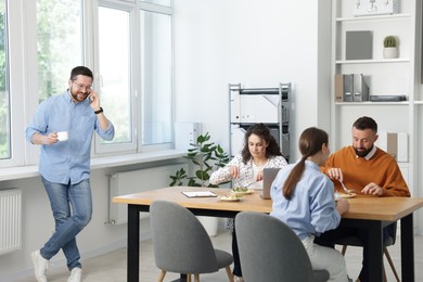 Photo of Colleagues eating and chatting during lunch break in office
