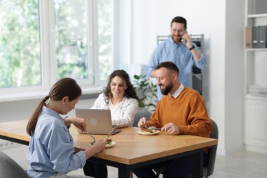Photo of Colleagues eating and chatting during lunch break in office