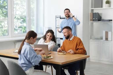Photo of Colleagues eating and chatting during lunch break in office