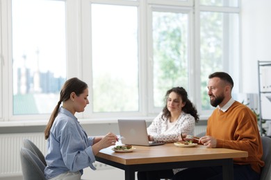Photo of Colleagues eating and chatting during lunch break in office