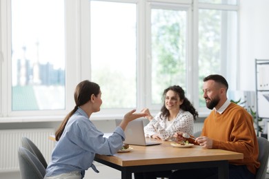 Photo of Colleagues eating and chatting during lunch break in office