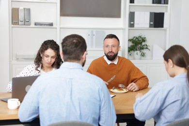 Photo of Colleagues eating and chatting during lunch break in office