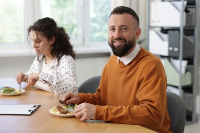 Photo of Colleagues eating and chatting during lunch break in office