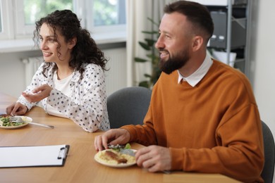 Photo of Colleagues eating and chatting during lunch break in office