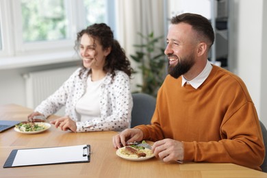 Photo of Colleagues eating and chatting during lunch break in office