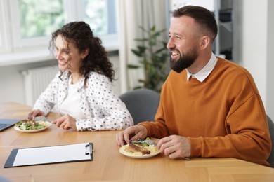 Photo of Colleagues eating and chatting during lunch break in office