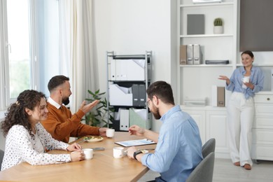 Photo of Colleagues eating and chatting during lunch break in office
