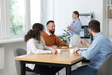 Photo of Colleagues eating and chatting during lunch break in office
