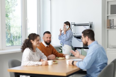 Photo of Colleagues eating and chatting during lunch break in office
