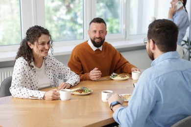 Photo of Colleagues eating and chatting during lunch break in office