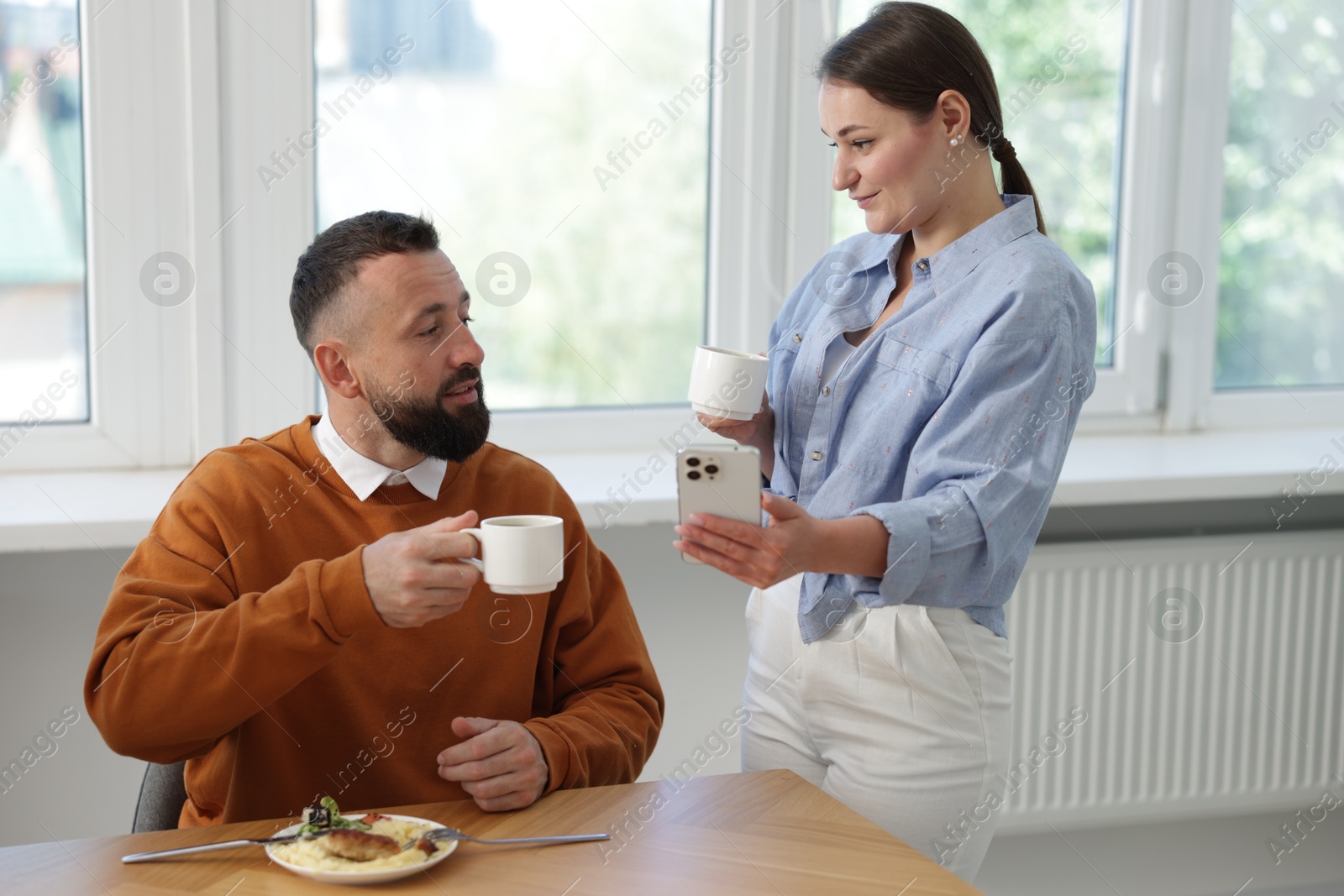 Woman showing her colleague something on smartphone during lunch break in office Photo of Woman showing her colleague something on smartphone during lunch break in office