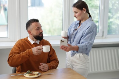 Photo of Woman showing her colleague something on smartphone during lunch break in office