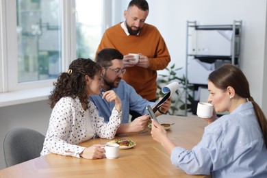 Photo of Colleagues eating and discussing work during lunch break in office