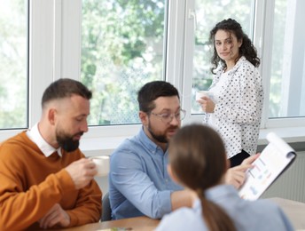 Photo of Colleagues eating and discussing work during lunch break in office