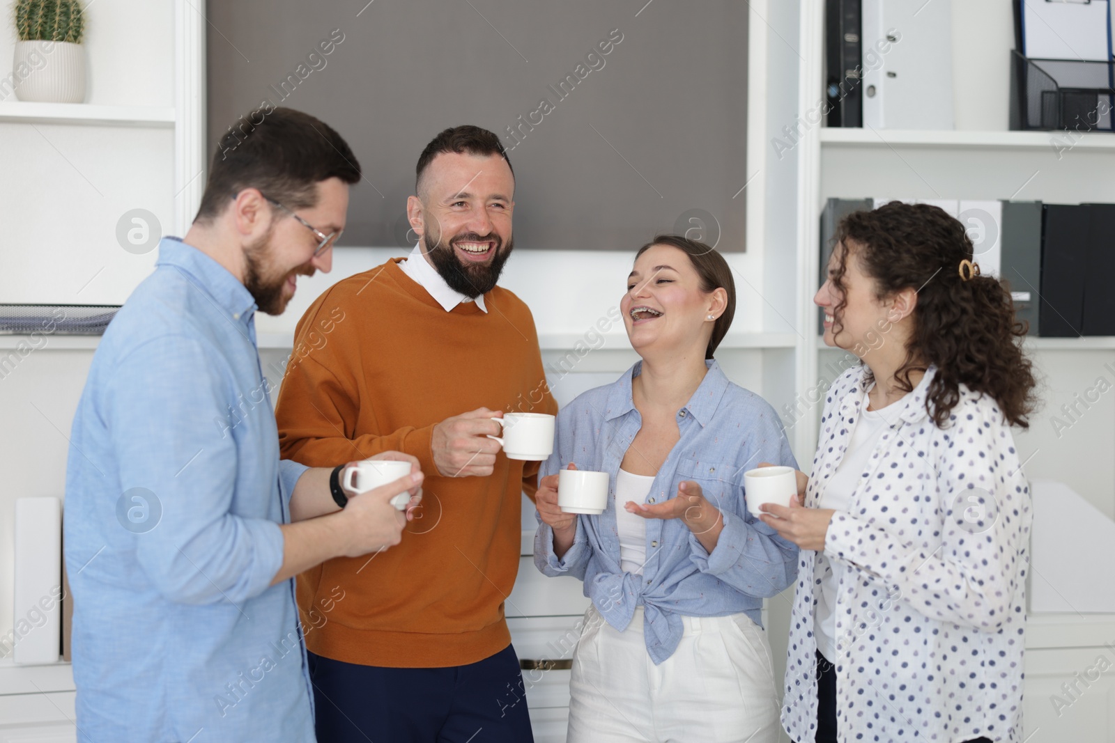 Colleagues chatting during coffee break in office Photo of Colleagues chatting during coffee break in office