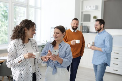 Photo of Colleagues chatting during coffee break in office