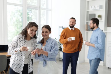 Photo of Colleagues chatting during coffee break in office