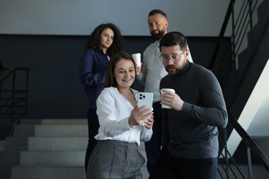 Photo of Colleagues with coffee on stairs in office during break