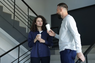 Photo of Colleagues with coffee on stairs in office during break