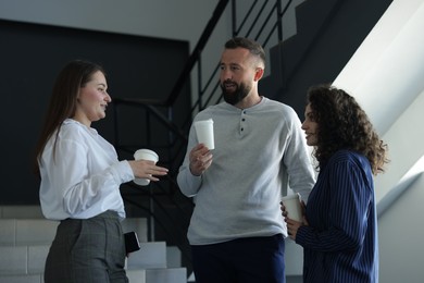 Photo of Colleagues with coffee on stairs in office during break
