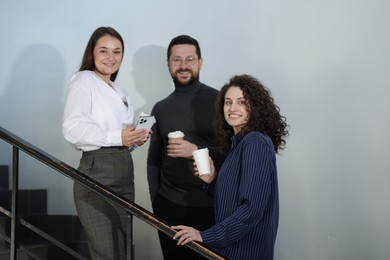 Photo of Colleagues with coffee on stairs in office during break