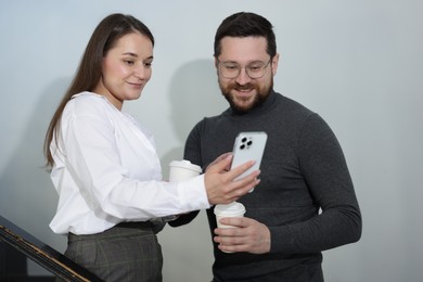 Photo of Colleagues with coffee on stairs in office during break