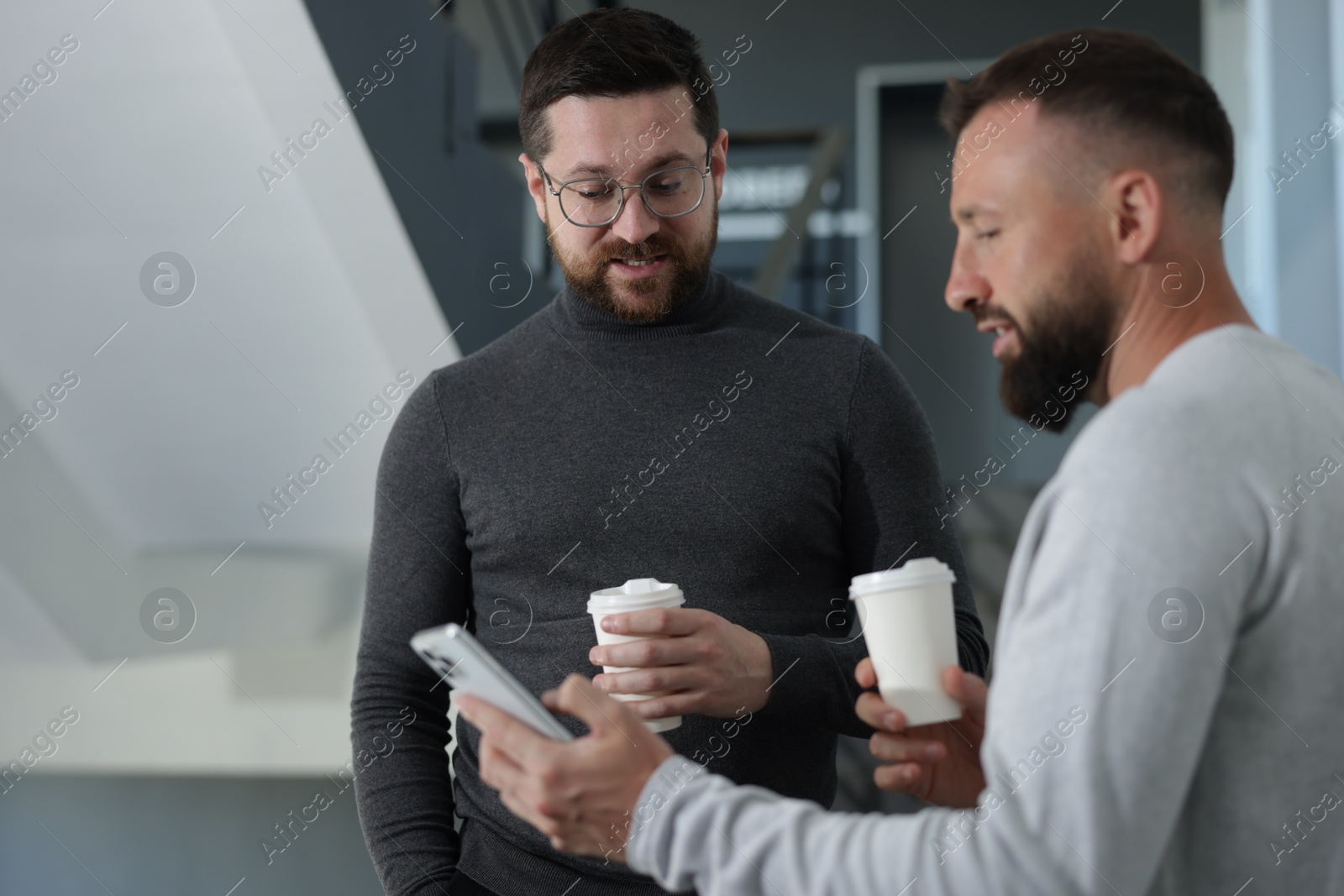 Colleagues with coffee on stairs in office during break Photo of Colleagues with coffee on stairs in office during break