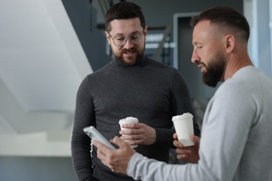 Photo of Colleagues with coffee on stairs in office during break