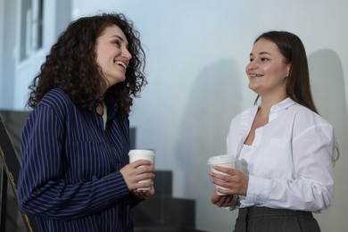 Photo of Colleagues with coffee on stairs in office during break