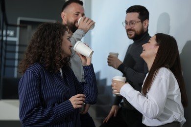 Photo of Colleagues with coffee on stairs in office during break