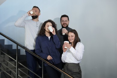 Photo of Colleagues with coffee on stairs in office during break