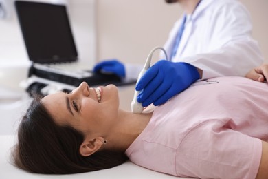 Photo of Sonographer conducting ultrasound examination of woman's thyroid gland in clinic, closeup