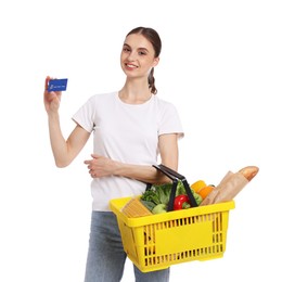 Photo of Woman with shopping basket full of products and credit card on white background