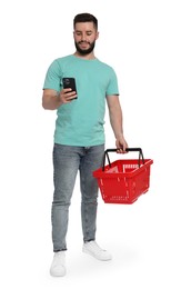 Photo of Man with empty shopping basket using smartphone on white background