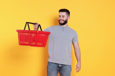 Photo of Man with empty shopping basket on orange background