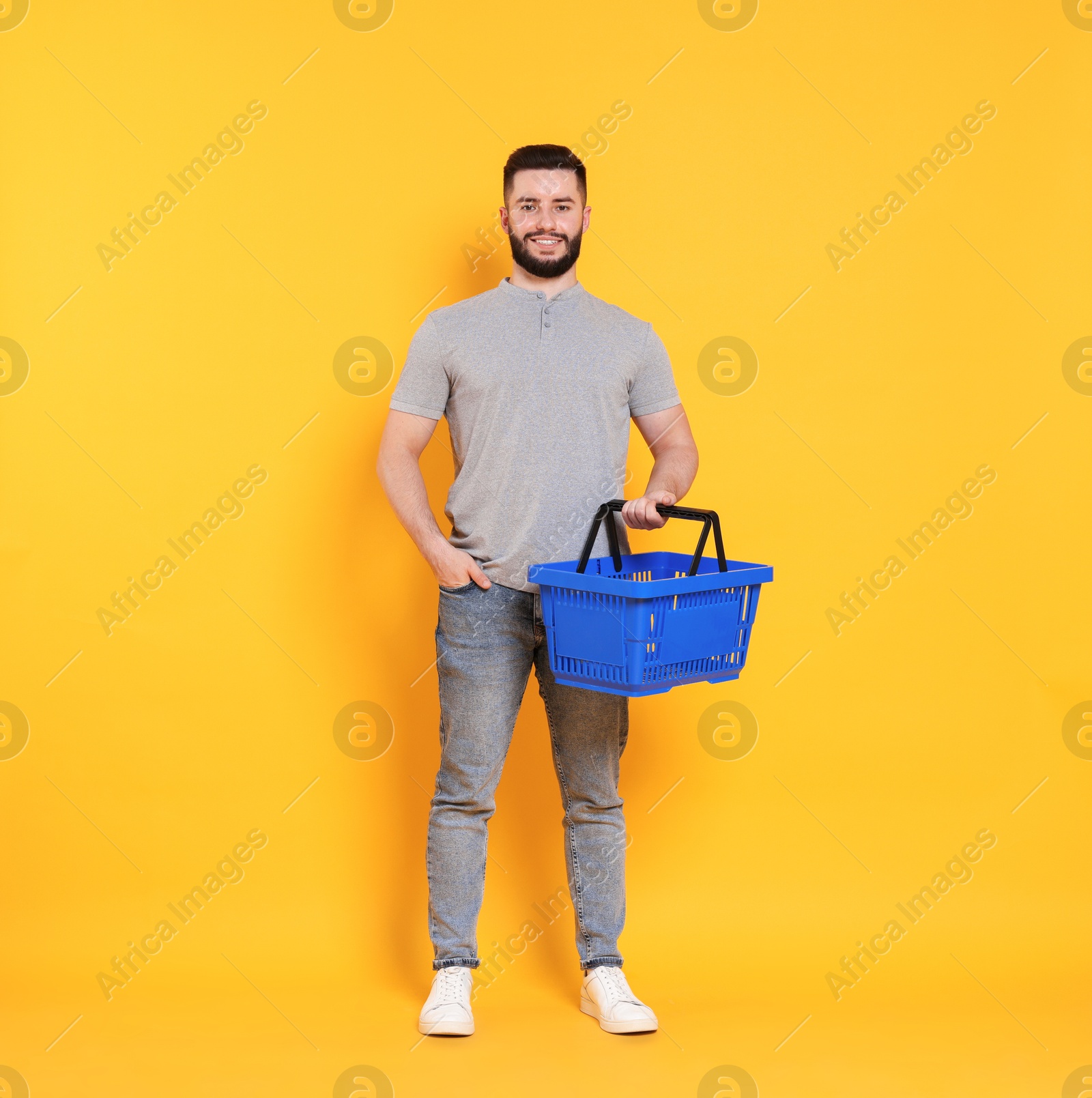 Man with empty shopping basket on orange background Photo of Man with empty shopping basket on orange background