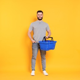 Photo of Man with empty shopping basket on orange background