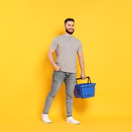 Photo of Man with empty shopping basket on orange background