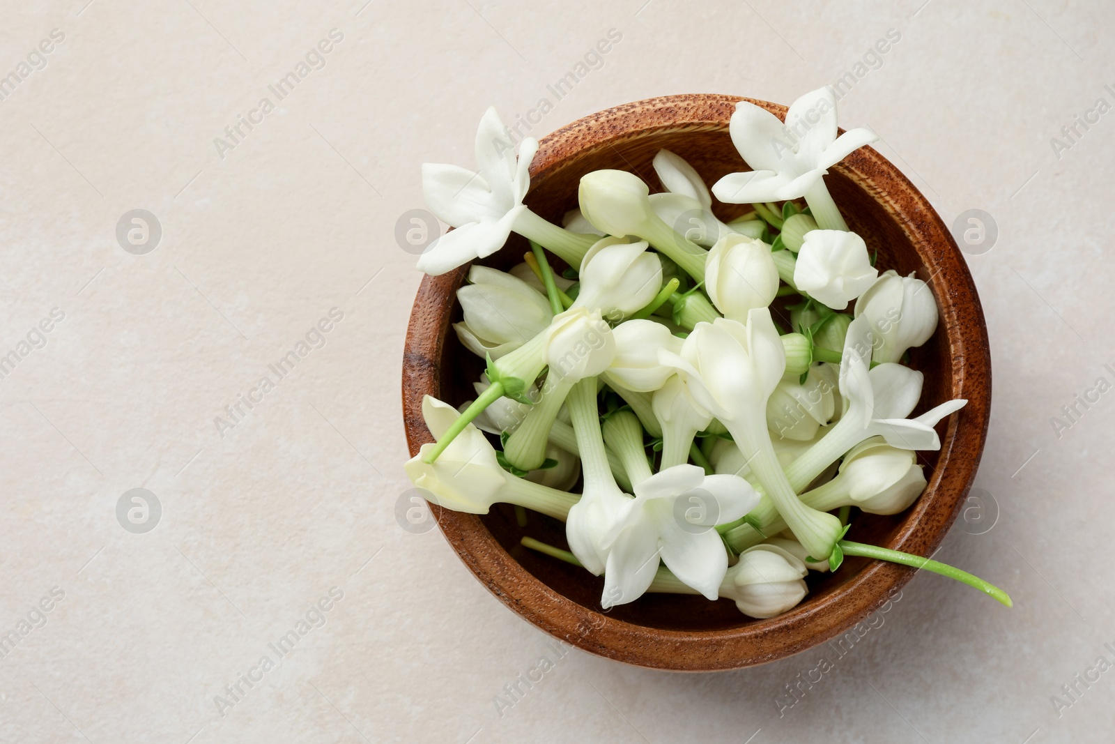 Bowl with jasmine flowers on beige table, top view. Space for text Photo of Bowl with jasmine flowers on beige table, top view. Space for text